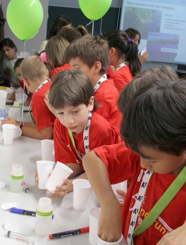 Kinder experimentieren mit Bechern und Flaschen in einem Labor.