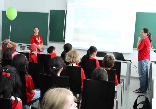 Eine Frau hält einen Vortrag vor einer Gruppe von Kindern.