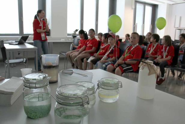 Eine Frau hält einen Vortrag vor einer Gruppe von Kindern in einem Klassenzimmer.