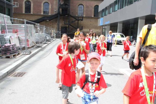 Eine Gruppe Kinder in roten T-Shirts geht eine Straße entlang.