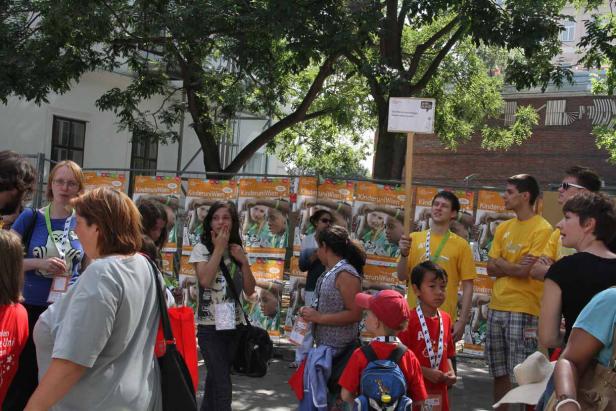 Eine Gruppe von Menschen steht vor Postern der Kinderuni Wien.
