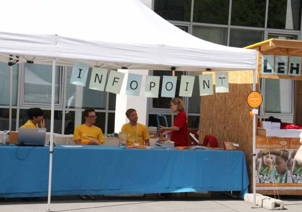Ein Infostand mit der Aufschrift „Infopoint“ und mehreren Personen davor.