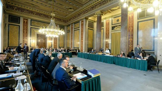 Eine formelle Sitzung mit vielen Teilnehmern in einem prunkvollen Saal.