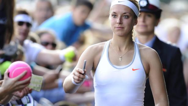 Eine Tennisspielerin mit Stirnband signiert Autogramme für Fans.