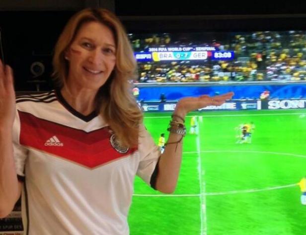 Eine Frau im Deutschland-Trikot schaut das WM-Halbfinale Deutschland gegen Brasilien (2014) im Fernsehen.