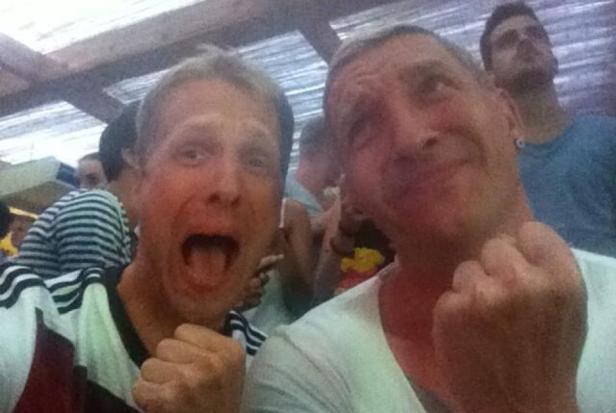 Zwei Männer, vermutlich deutsche Fußballfans, jubeln mit geballten Fäusten.