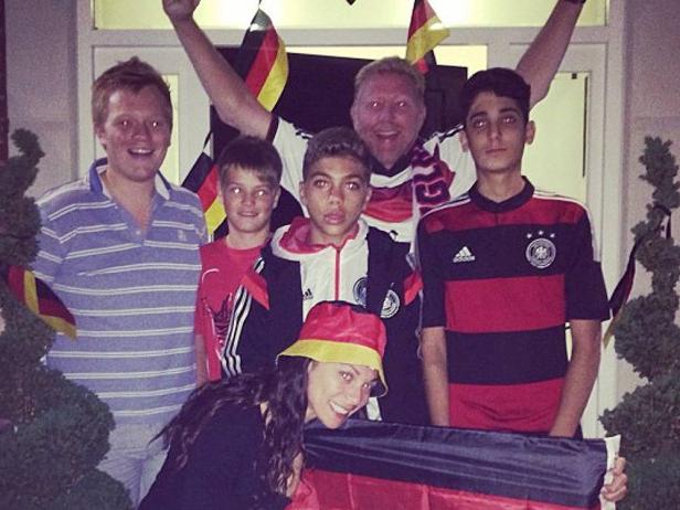 Eine Gruppe von Menschen, einige in Deutschland-Trikots, posiert mit Deutschland-Flaggen.