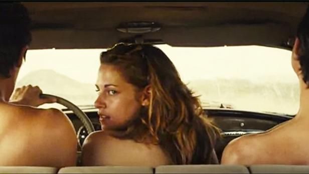 Kristen Stewart sitzt zwischen zwei Männern in einem Auto und blickt über ihre Schulter.