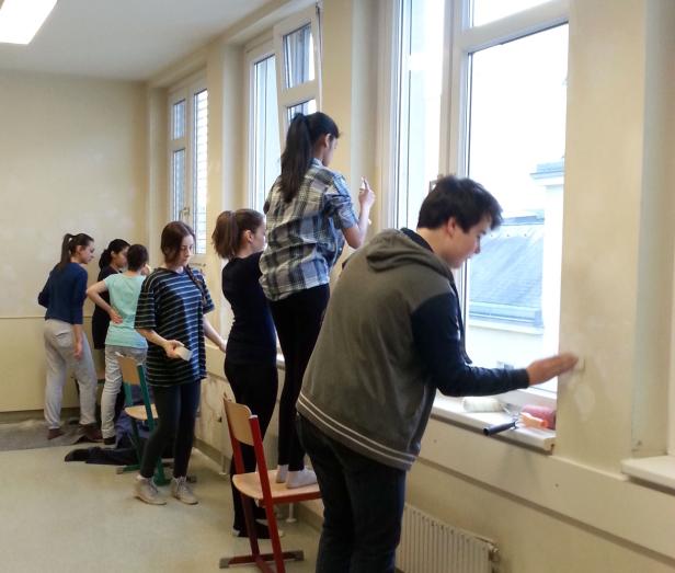 Eine Gruppe von Jugendlichen streicht einen Klassenraum.