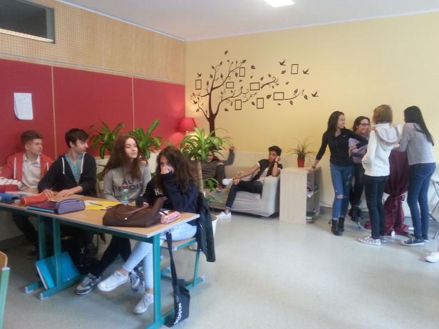 Eine Gruppe von Schülern sitzt und steht in einem Klassenzimmer.