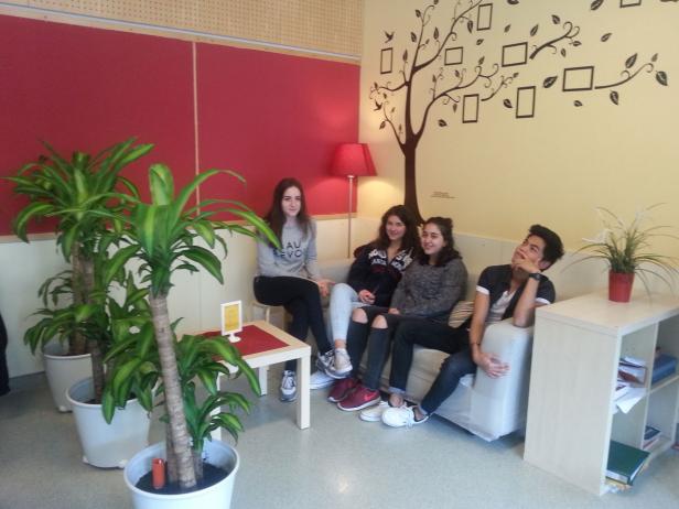 Vier Jugendliche sitzen in einem Aufenthaltsraum auf einem Sofa.