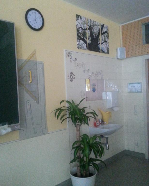 Ein Waschbecken und eine Zimmerpflanze stehen in einem Raum mit Fliesen und Dekorationen.