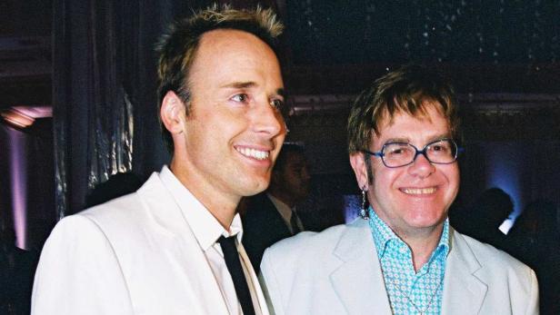 David Furnish und Elton John posieren lächelnd für ein Foto.