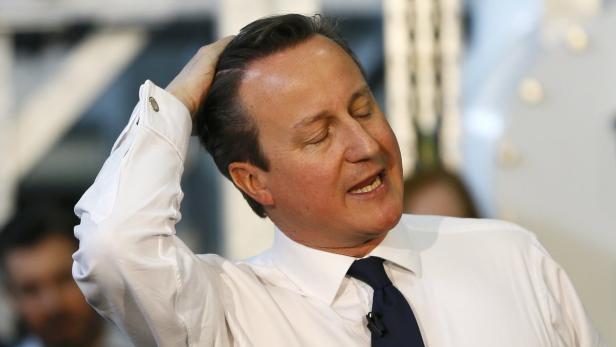 David Cameron gestikuliert mit der Hand auf seinem Kopf.