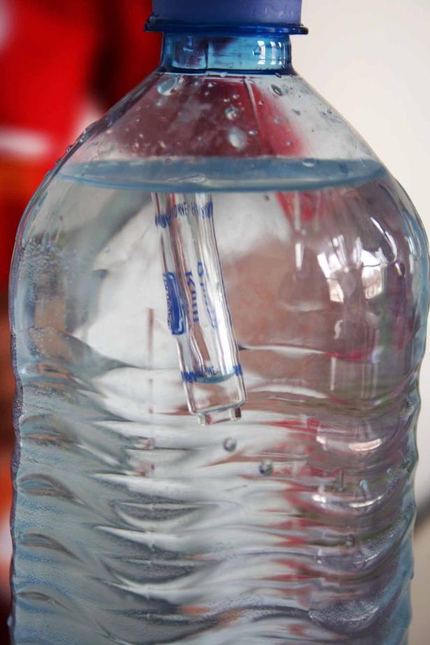 Eine Plastikwasserflasche mit einem Strohhalm darin.