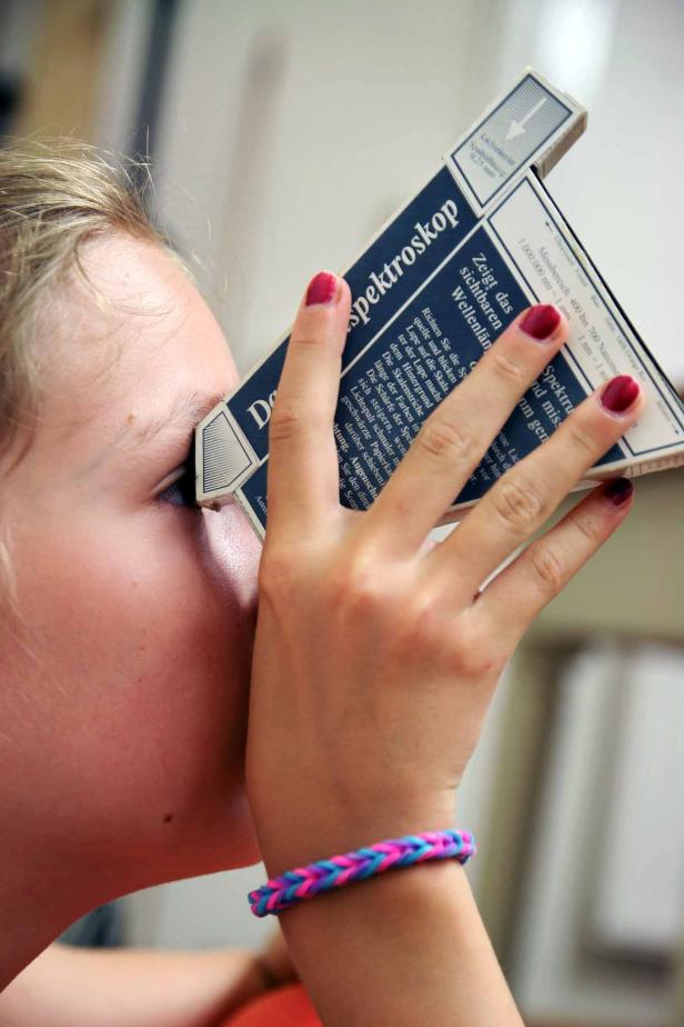 Ein Mädchen blickt durch ein Spektroskop.