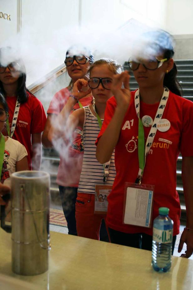 Eine Gruppe Kinder mit Schutzbrillen experimentiert mit Trockeneis und erzeugt Nebel.