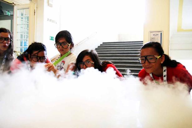 Eine Gruppe von Kindern mit Schutzbrillen experimentiert mit Trockeneis.