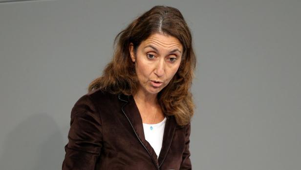 Eine Frau mit braunem Haar und braunem Blazer spricht.