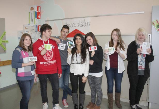 Eine Gruppe junger Leute präsentiert verschiedene Gütesiegel für Lebensmittel.