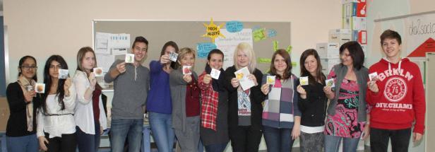 Eine Gruppe von Schülern hält Bilder von Obst und Gemüse hoch.