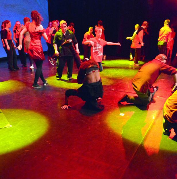 Eine Gruppe von Tänzern führt eine Choreografie auf einer Bühne auf.