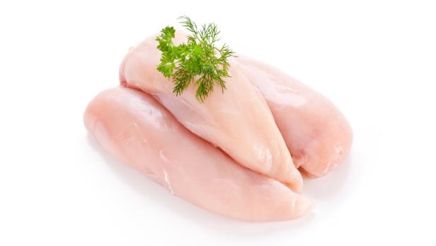 Drei rohe Hähnchenbrustfilets, garniert mit Dill und Petersilie.