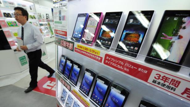 Ein Mann geht an einem Regal mit ausgestellten Sony Ericsson Xperia Smartphones vorbei.