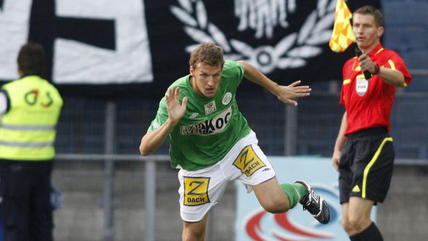 Ein Fußballspieler in Grün wird von einem Linienrichter beobachtet.