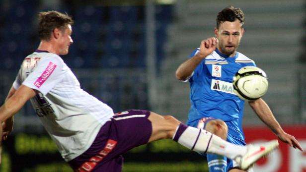 Zwei Fußballspieler kämpfen um den Ball während eines Spiels.