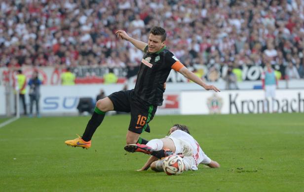 Ein Fußballspieler von Werder Bremen grätscht einen Gegenspieler ab.
