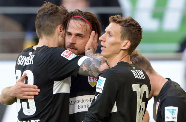 Fußballspieler des VfB Stuttgart umarmen sich auf dem Spielfeld.