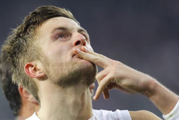 Ein Mann mit Bart hält einen Finger an die Lippen und blickt nach oben.