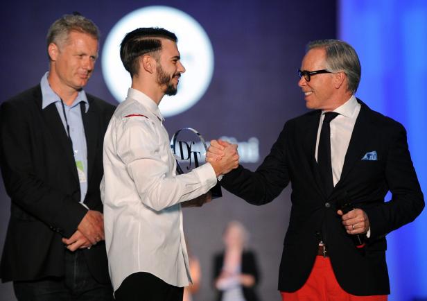 Zwei Männer schütteln sich die Hände, während ein dritter Mann daneben steht.