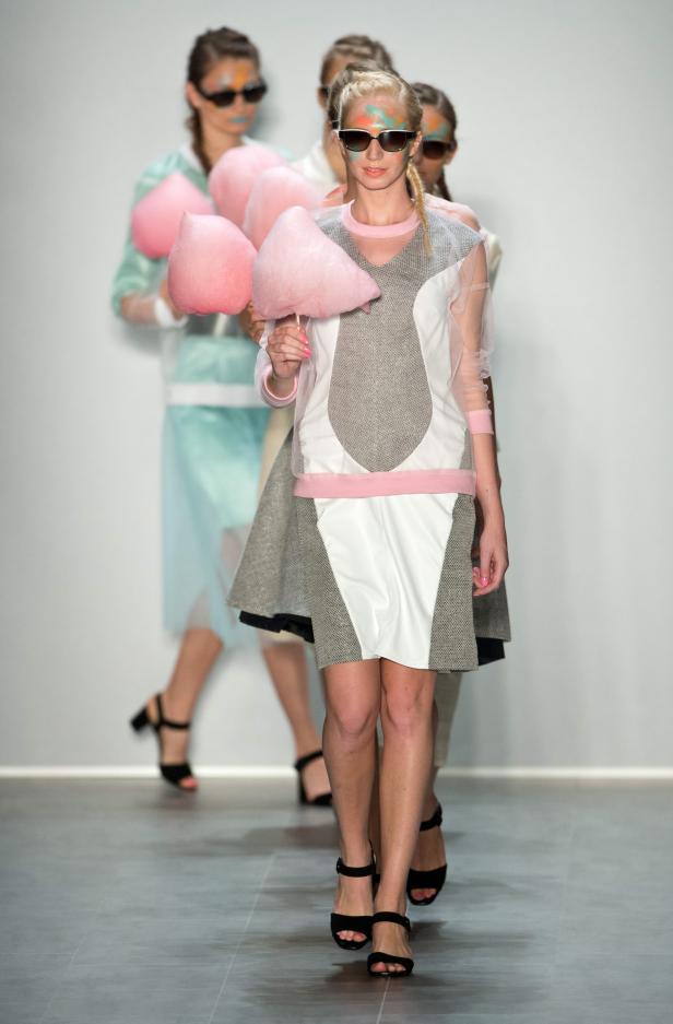 Models mit farbiger Gesichtsbemalung und Sonnenbrillen präsentieren Mode und Zuckerwatte auf dem Laufsteg.