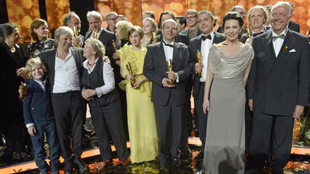 Die Preisträger, gemeinsam mit Schauspielerin Iris Berben (2.v.re.) auf der Bühne. Sie ist Präsidentin der Deutschen Filmakademie. Eine Gruppe von Menschen posiert mit goldenen Statuen auf einer Bühne.