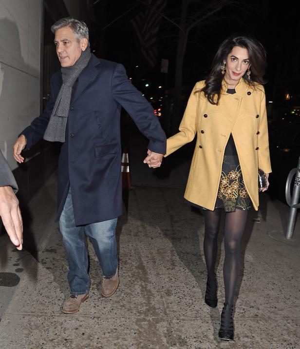 George und Amal Clooney gehen Händchen haltend die Straße entlang.