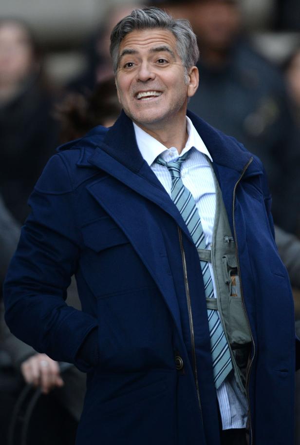 George Clooney lächelt in einem blauen Mantel.