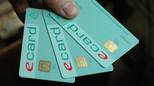 Eine Hand hält drei E-Cards der Sozialversicherung.