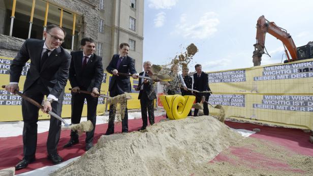 Mehrere Personen beim Spatenstich mit gelbem Post-Logo im Vordergrund.