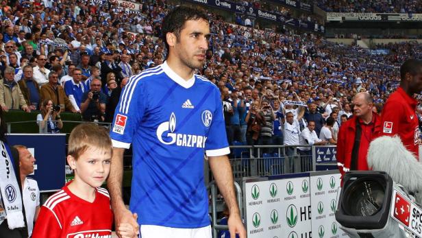 Ein Fußballspieler des FC Schalke 04 mit einem Kind im Stadion.