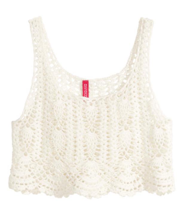 Ein weißes, gehäkeltes Tanktop vor einem weißen Hintergrund.