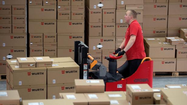 Ein Arbeiter fährt einen Gabelstapler vor einem Lager voller Würth-Kartons.