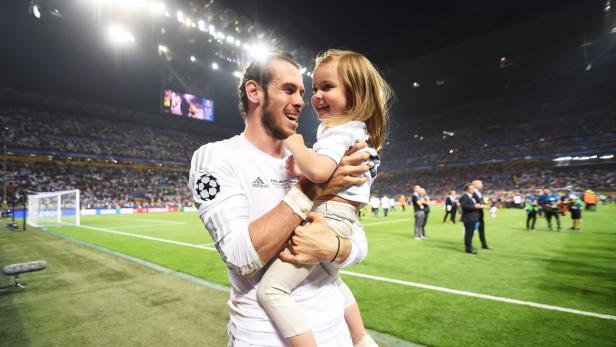 Gareth Bale feiert mit seiner Tochter auf dem Fußballfeld.