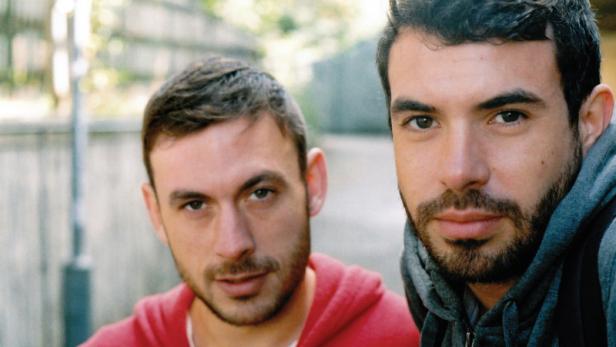 Zwei junge Männer mit Bärten schauen in die Kamera.