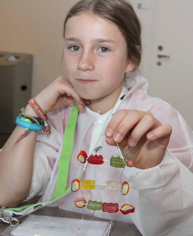 Ein Mädchen präsentiert eine DNA-Doppelhelix aus Gummibärchen.
