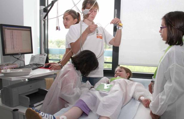 Ein junges Mädchen liegt in einem Krankenhausbett, während Ärzte sie untersuchen.