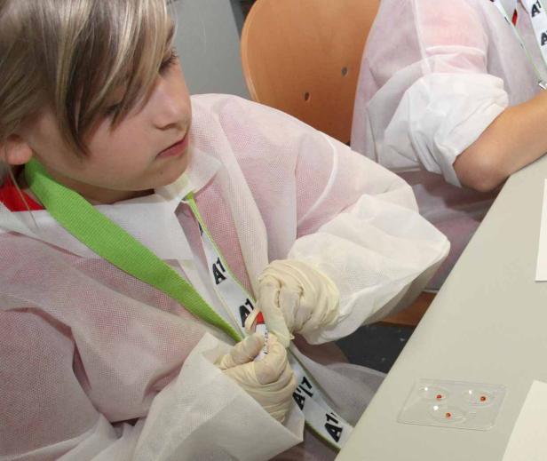Ein Kind im Laborkittel führt einen Bluttest durch.