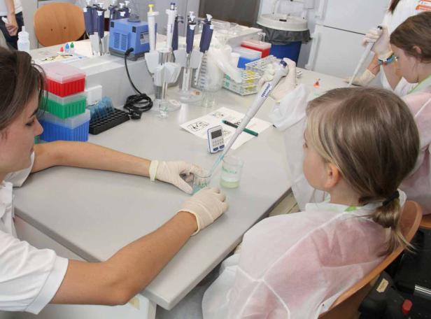 Kinder experimentieren mit Pipetten und Bechergläsern im Labor.