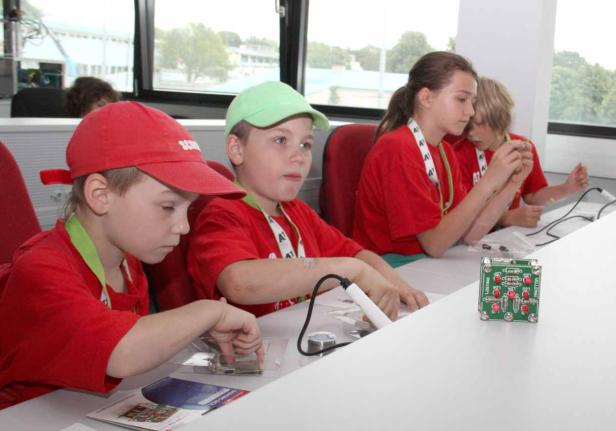 Eine Gruppe Kinder arbeitet an einem Elektronikprojekt mit Lötkolben.
